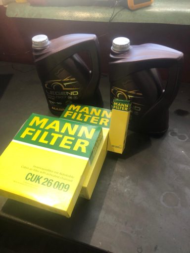 Zwei Flaschen Motoröl und eine gelbe Kiste von Mann-Filter auf einem Tisch.
