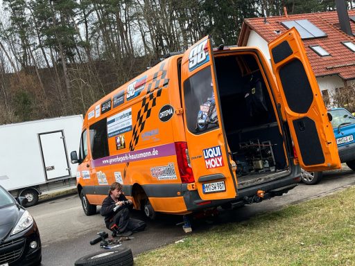 Oranger Transporter mit offener Heckklappe, Techniker repariert Reifen.
