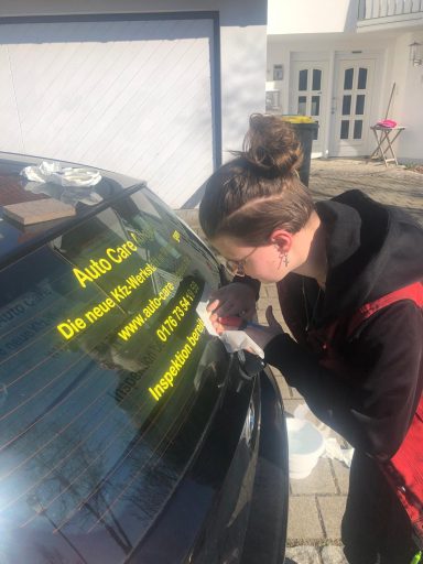 Frau klebt ein gelbes Schild mit Werbung an eine Autotür.