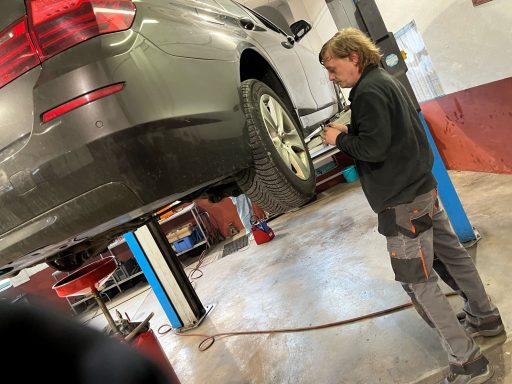 Mechaniker überprüft ein Auto, das auf einer Hebebühne steht.