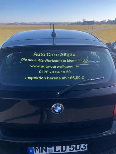 Aufkleber auf einem schwarzen Auto mit Kontaktdaten und Website für einen Autoservice.